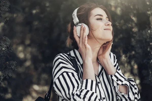 Outdoor Summer Portrait of Young Beautiful Girl in White Striped Stylish Dress Listens Music in Headphones — Stock Photo, Image