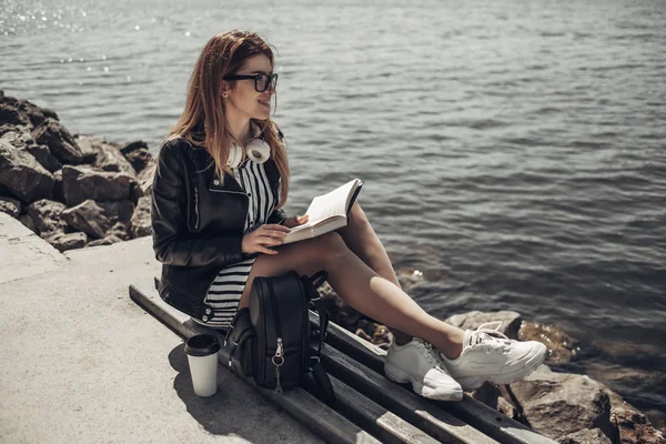 Outdoor Summer Portrait of Young Beautiful Girl in Black Leather Jacket and Glasses Reads the Book Near the Lake — Stock Photo, Image