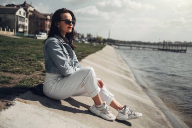 Göl kenarında Güneş Gözlüğü Beyaz Pantolon ve Jeans Ceket Güzel Esmer Kız