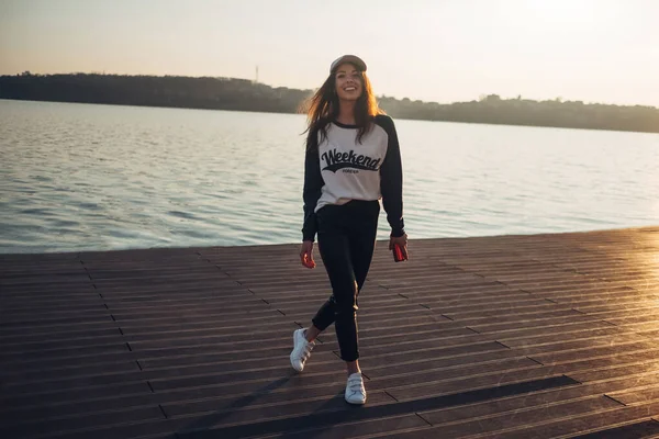 Piękna młoda dziewczyna Hipster w swetrze z tekstem "weekend Forever" chodzenie w plaży o zachodzie słońca — Zdjęcie stockowe