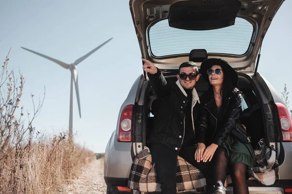 Elektrikli Rüzgâr Türbini Güç Üreteç 'iyle Tadını Çıkaran Mutlu Seyahat Çifti Saha Yolundaki Bagajda Oturuyor — Stok fotoğraf