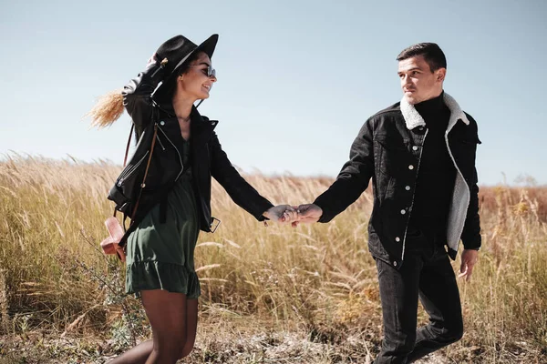 Портрет счастливой пары, одетой в черную стильную одежду, наслаждающейся хорошей прогулкой по полю — стоковое фото