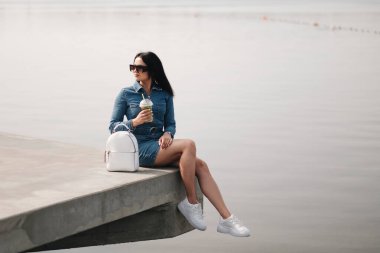 Kot pantolon giymiş güzel bir esmer kız Tulum giyiyor Kokteyl içiyor