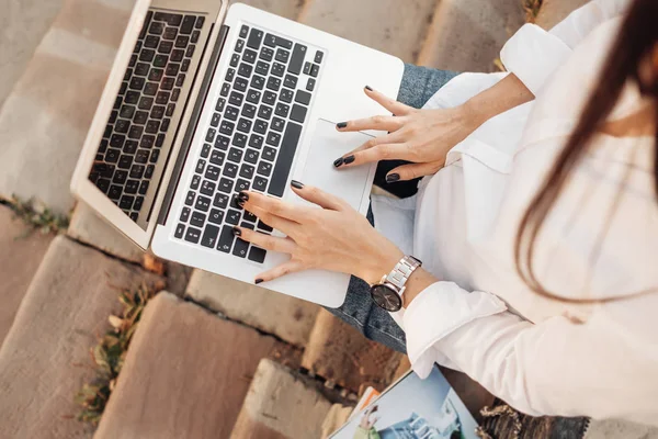 Retrato de uma menina na moda vestida de jeans e camisa branca trabalhando no laptop, trabalhador freelance, senhora de negócios, conceito de poder da mulher — Fotografia de Stock