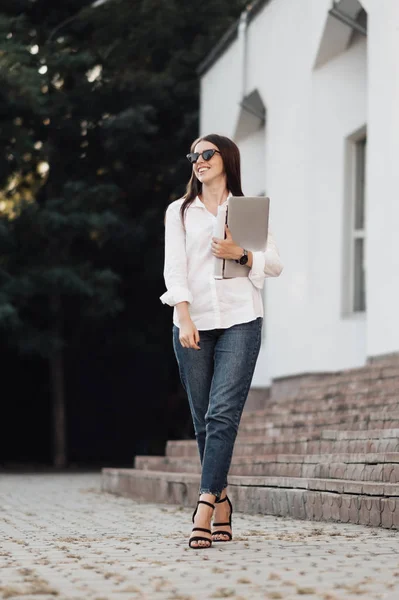 Retrato de una chica de moda vestida con vaqueros y camisa blanca que sostiene el ordenador portátil, trabajador independiente, dama de negocios, concepto de poder de la mujer — Foto de Stock