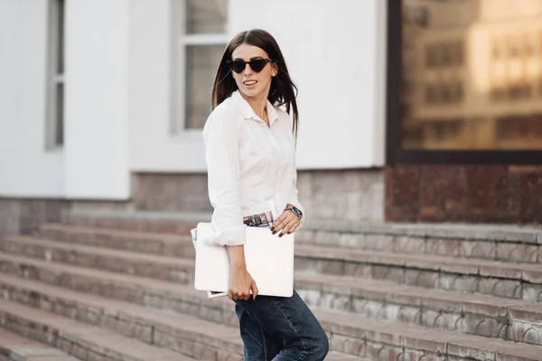 Retrato de una chica de moda vestida con vaqueros y camisa blanca que sostiene el ordenador portátil, trabajador independiente, dama de negocios, concepto de poder de la mujer — Foto de Stock