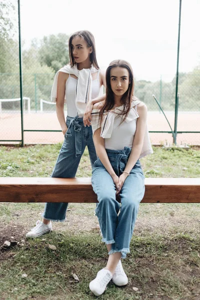 Portré két fiatal barna ikrek nővérek öltözött Alike farmer és fehér póló, legjobb barátok Forever Concept — Stock Fotó