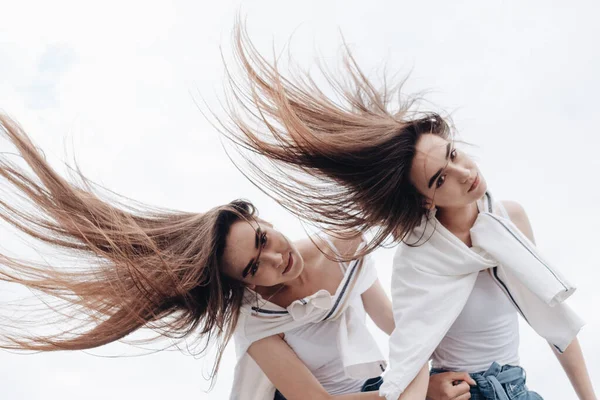 Retrato de dos hermanas gemelas morenas jóvenes vestidas como en pantalones vaqueros y camiseta blanca, mejor concepto de amigos para siempre —  Fotos de Stock