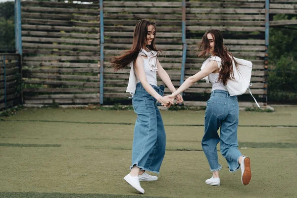 Retrato de dos hermanas gemelas morenas jóvenes vestidas como en pantalones vaqueros y camiseta blanca, mejor concepto de amigos para siempre —  Fotos de Stock