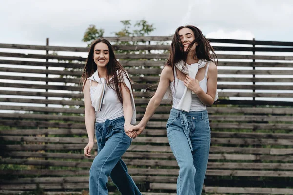Portré két fiatal barna ikrek nővérek öltözött Alike farmer és fehér póló, legjobb barátok Forever Concept — Stock Fotó