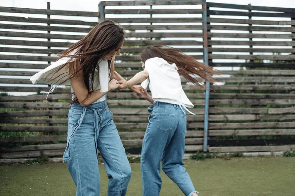 Portret van twee jonge Brunette tweeling zusters gekleed als in jeans en wit T-shirt, beste vrienden voor altijd concept — Stockfoto