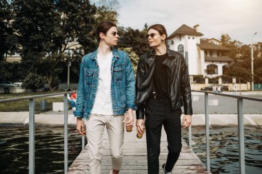 İki Şık İkiz Kardeş Nehir kenarındaki İskelede Eğlence İçen Bira İçiyorlar