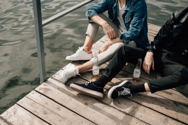 İki Şık İkiz Kardeş Nehir kenarındaki İskelede Eğlence İçen Bira İçiyorlar