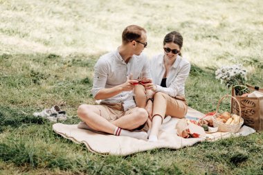 Beyaz tişörtlü genç mutlu çift piknikte eğleniyor, haftasonu şehir dışında, tatil konsepti.