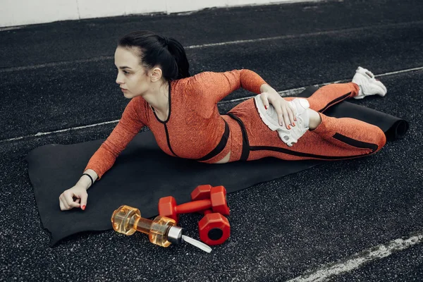 Retrato de una chica deportiva vestida con ropa deportiva haciendo estiramientos Ejercicio y entrenamiento en el estadio de la ciudad, concepto de estilo de vida saludable — Foto de Stock