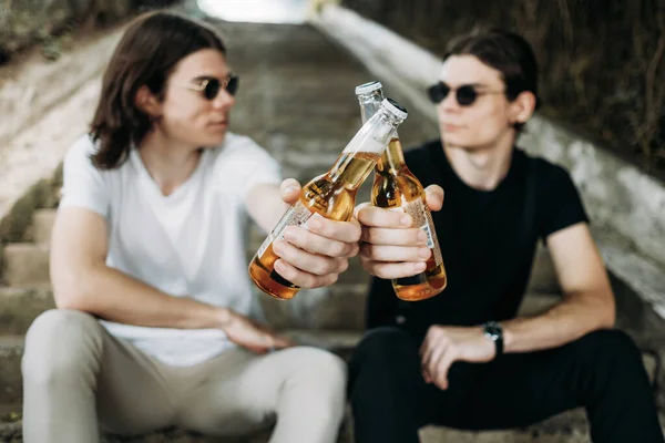Due fratelli gemelli alla moda che si divertono a bere birra sulle scale — Foto Stock