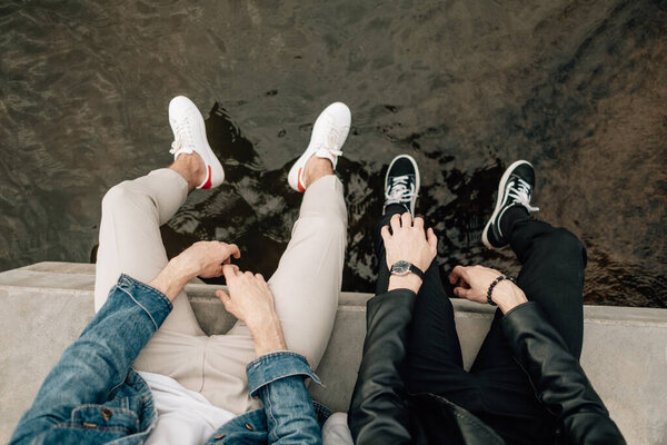 Два стильных брата-близнеца позируют на пирсе у реки
