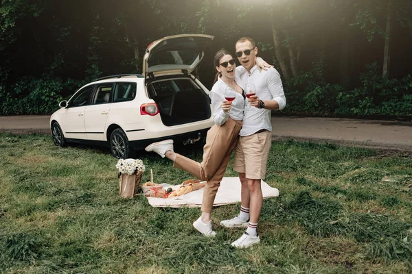 Joven pareja feliz vestida como en camiseta blanca divirtiéndose cerca del coche, fin de semana fuera de la ciudad, días festivos y concepto de viaje por carretera — Foto de Stock