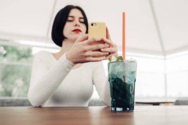 Beyaz Süveterli Güzel Esmer Kızın Cep Telefonu Kullanarak Yakın Portresi