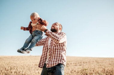 Küçük oğluyla mutlu bir baba. Yaz haftasının tadını çıkarıyor. Güneşli gün batımında şehrin dışındaki kırda.