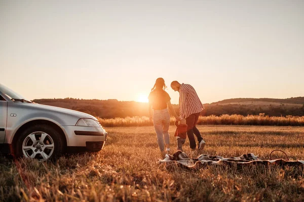 Glad ung familj mamma och pappa med sin lilla son Njuter av sommar helg picknick på bilen utanför staden i fältet på soliga dagen solnedgång, semester och väg resa koncept — Stockfoto