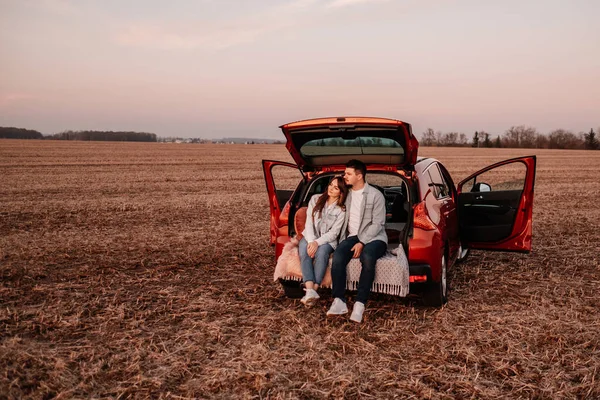 Beyaz Gömlekli ve Kot Giyen Genç Mutlu Çift Yeni Araba Bagajlarında Oturuyor, Sahada Güzel Günbatımı, Tatil ve Seyahat Konsepti — Stok fotoğraf