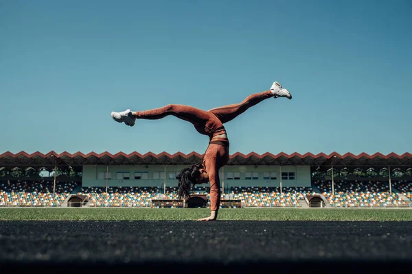 Retrato de um esporte Fitness Girl Vestida Moda Sportswear Roupa Fazendo Handstand Exercício e vira no Estádio da Cidade, conceito de estilo de vida saudável — Fotografia de Stock