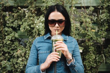 Kot pantolon giymiş güzel bir esmer kız Tulum giyiyor Kokteyl içiyor