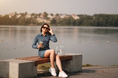 Kot pantolon giymiş güzel bir esmer kız Tulum giyiyor Kokteyl içiyor