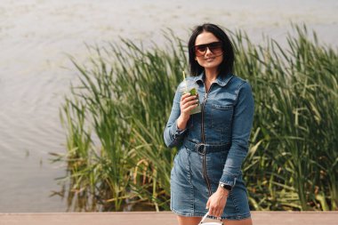 Kot pantolon giymiş güzel bir esmer kız Tulum giyiyor Kokteyl içiyor