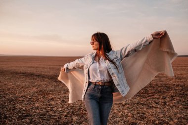 Beyaz gömlekli ve kot ceketli güzel bir kızın portresi, Sunset 'te şehrin dışında iyi vakit geçiriyor.