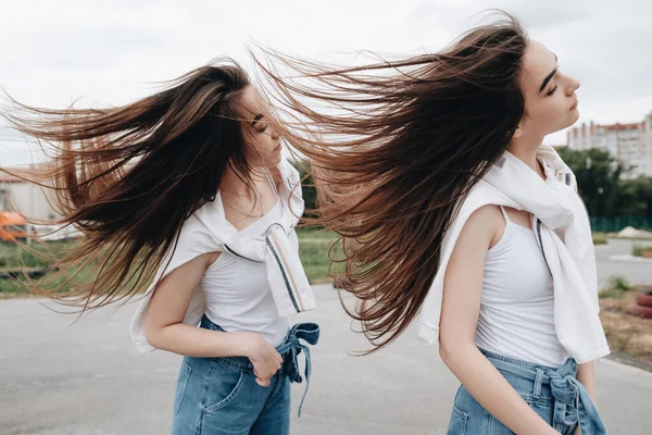 Porträt von zwei brünetten Zwillingsschwestern in Jeans und weißem T-Shirt, beste Freundinnen für immer — Stockfoto