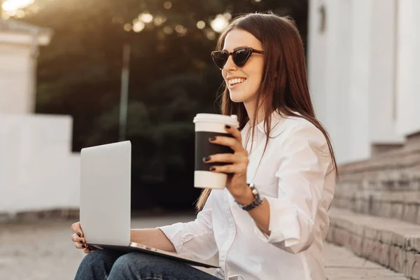 Portré egy divatos lány öltözött farmer és fehér ing gazdaság Laptop és forró kávé, szabadúszó munkavállaló, Business Lady, nő Power Concept — Stock Fotó