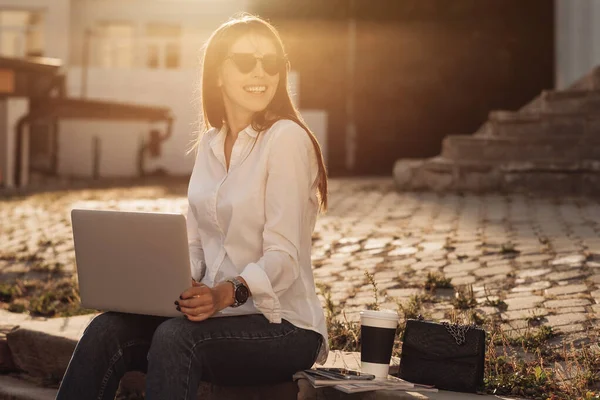 Retrato de uma menina na moda vestida em jeans e camisa branca segurando laptop, trabalhador freelance, senhora de negócios, conceito de poder da mulher — Fotografia de Stock