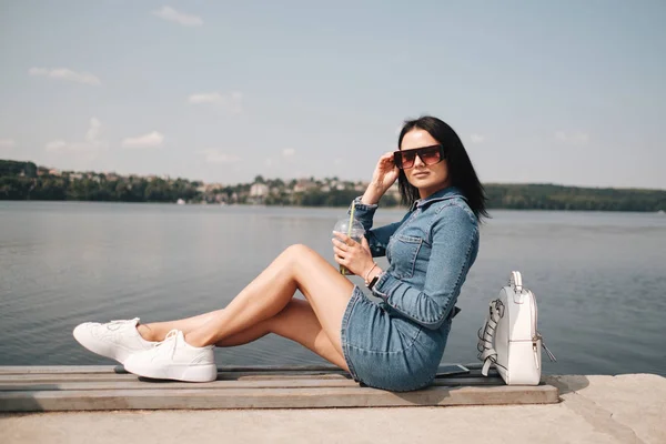 Portrét jedné krásné brunety dívka oblečená v džínách džínové kombinézy tráví volný čas — Stock fotografie