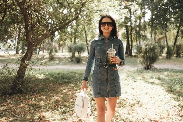 Portret jednej pięknej dziewczyny Brunetki ubranej w dżinsy Spacery w jesiennym parku — Zdjęcie stockowe