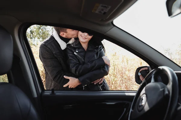 Felice coppia di viaggio vestita di nero abiti eleganti godendo di un viaggio in auto sulla strada di campo, concetto di vacanza — Foto Stock