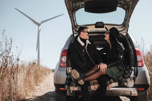 Happy Traveling Pasangan Menikmati Perjalanan Mobil Duduk di Trunk di Lapangan Jalan dengan Angin Listrik Turbin Power Generator — Stok Foto