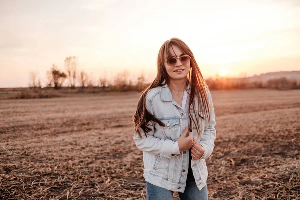 Portré Egy Gyönyörű Stílusos Lány Öltözött Fehér Ing És Jeans Jacket, Szórakozás Kívül A Város A Field Napnyugtakor — Stock Fotó