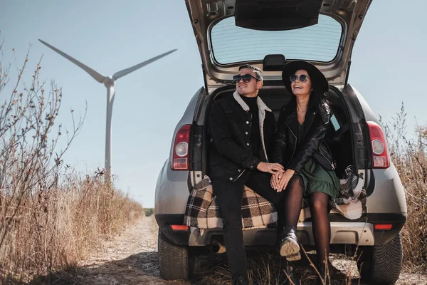 Elektrikli Rüzgâr Türbini Güç Üreteç 'iyle Tadını Çıkaran Mutlu Seyahat Çifti Saha Yolundaki Bagajda Oturuyor — Stok fotoğraf