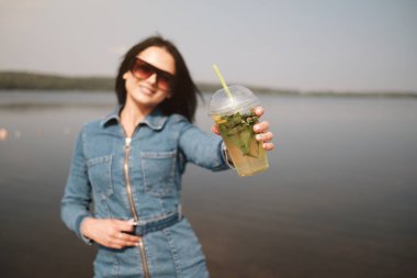 Kot pantolon giymiş güzel bir esmer kız Tulum giyiyor Kokteyl içiyor