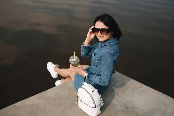 Portret van een mooi Brunette meisje gekleed in jeans jeans Overalls brengt vrije tijd — Stockfoto