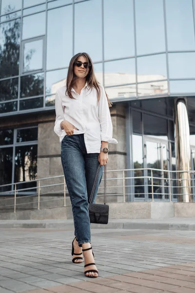 Retrato de uma menina na moda vestida de jeans e camisa branca, senhora de negócios, conceito de poder da mulher — Fotografia de Stock