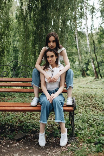 Retrato de dos hermanas gemelas morenas jóvenes vestidas como en pantalones vaqueros y camiseta blanca, mejor concepto de amigos para siempre — Foto de Stock