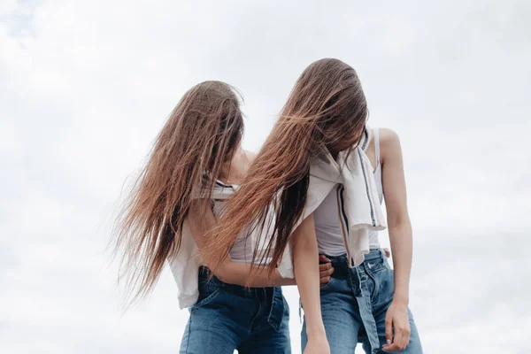 Portret van twee jonge Brunette tweeling zusters gekleed als in jeans en wit T-shirt, beste vrienden voor altijd concept — Stockfoto