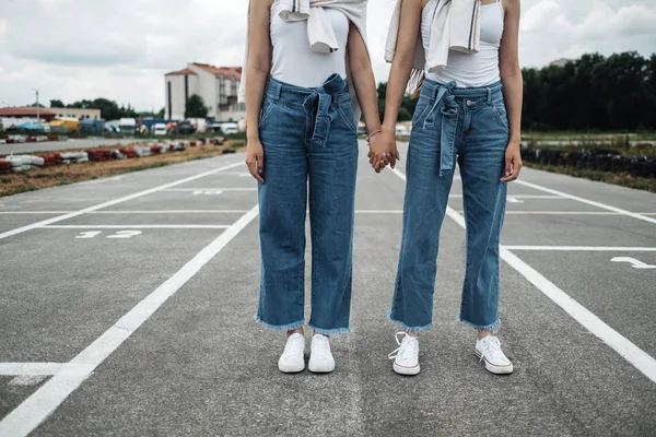 Retrato de dos hermanas gemelas morenas jóvenes vestidas como en pantalones vaqueros y camiseta blanca, mejor concepto de amigos para siempre —  Fotos de Stock