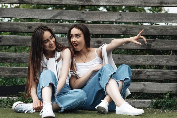 Retrato de dos hermanas gemelas morenas jóvenes vestidas como en pantalones vaqueros y camiseta blanca, mejor concepto de amigos para siempre — Foto de Stock