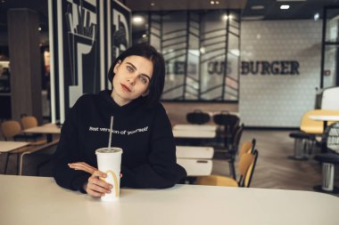 Ternopil, Ukrayna - 25 Mayıs 2019: Siyah Kazaklı Güzel Esmer Kız 'McDonalds' ta Coca-Cola İçiyor
