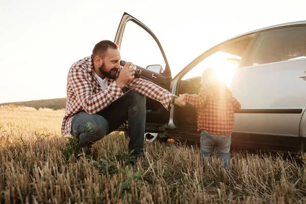 Küçük oğluyla mutlu bir baba. Yaz haftasının tadını çıkarıyor. Güneşli gün batımında şehrin dışındaki kırda.