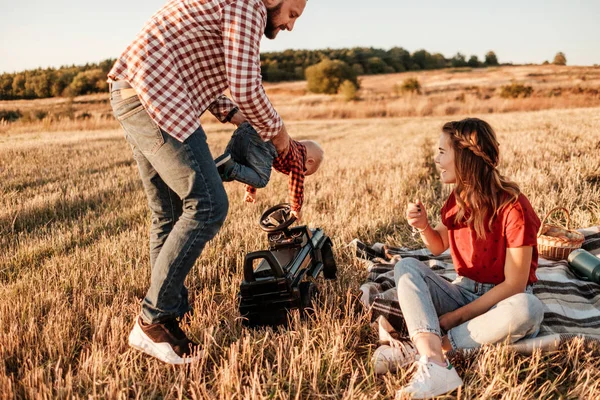 Happy Young Family Mom and Dad with Their Little Son Enjoying Summer Weekend Picnic Outside the City in the Field at Sunny Day Sunset, Vacation Time Concept — Stok Foto